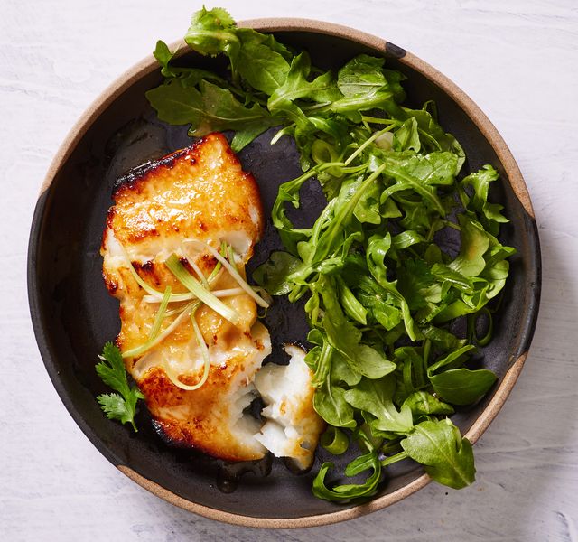 miso marinated chilean sea bass with wilted arugula on a black plate