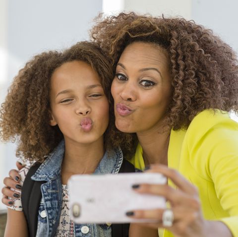 Mixed race mother and daughter taking selfie
