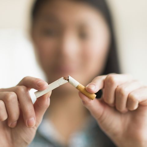 mixed race teenage girl breaking cigarette in half