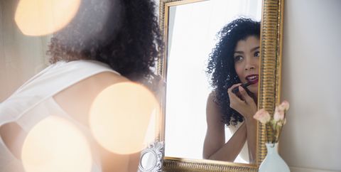 Mixed race woman applying lipstick in mirror