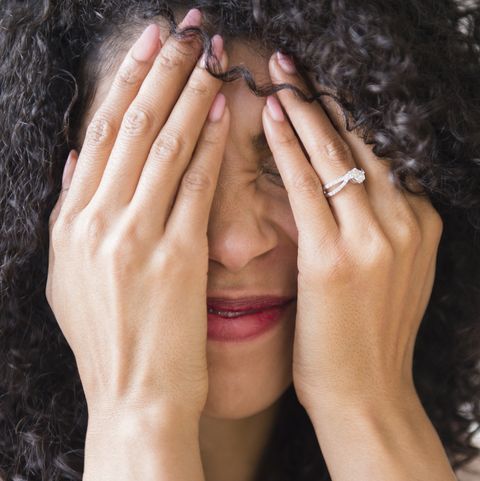 Mixed race woman with curly hair covering her face