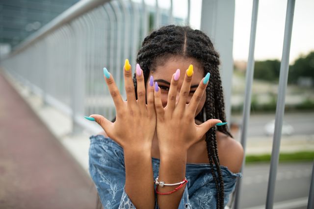 een vrouw toont haar kleurrijke, lange nagels