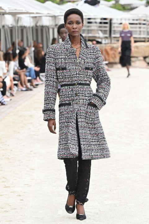 chanel model walks the runway wearing tweed coat