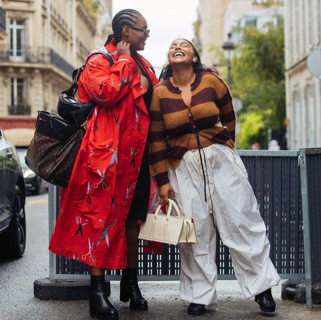 two models stand on a busy street to illustrate net a porters black friday 2021 designer sale