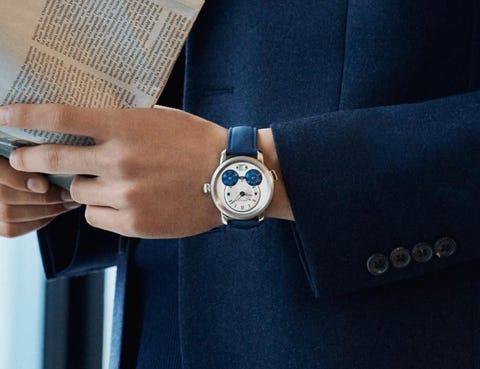 a man with a montblanc watch and reading a newspaper