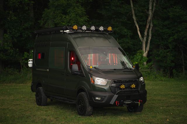 a van with a large rack on the back parked in a grassy area