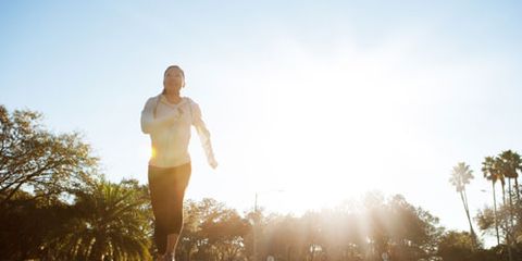 Female runner running at sunrise through a park