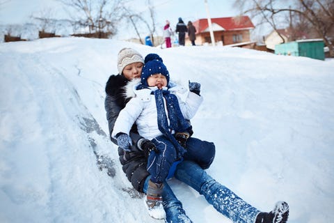 Мать и дочь катаются на санях на заснеженном поле