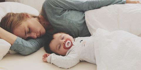 Mother And Son Sleeping On Bed At Home