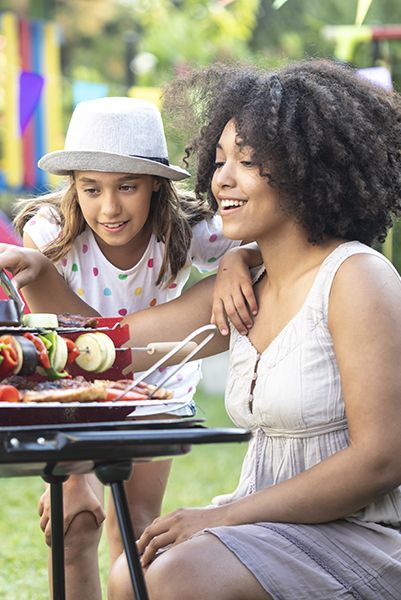 mother and daughter preparing tasty barbecue on back yard bbqing is a gh idea for best mother's day activity
