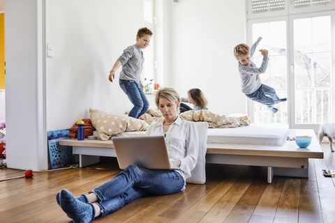 madre trabajando desde casa con sus hijos jugando