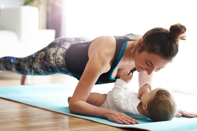 mother with baby exercising on yoga mat at home
