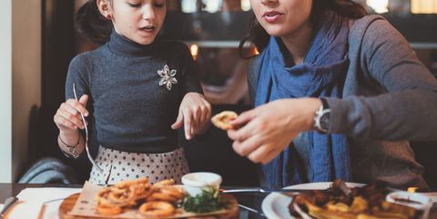 Mother with daughter eating in restaurant at dinner