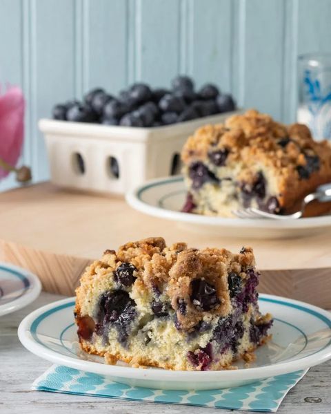blueberry buckle slice on plate with blueberries in white box