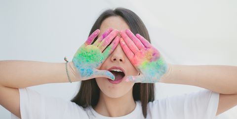 young brunette girl covering eyes with dirty painted eyes