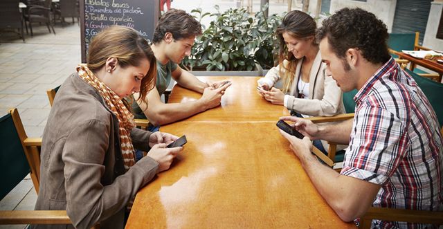varias personas atienden al móvil durante una reunión de amigos