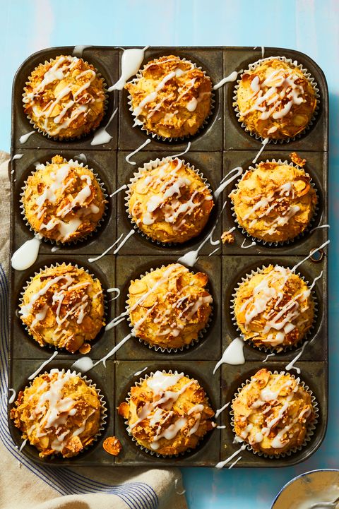 lemon almond poppy seed muffins in a muffin tin tray and icing drizzled on top