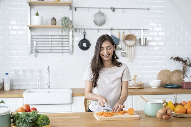 mujer cortando zanahoria en la cocina de su casa