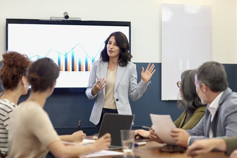 una mujer ofrece a sus compañeros una presentación con gráficos en la sala de reuniones de una oficina