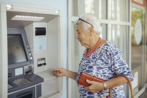 una señora jubilado, tarjeta en mano, se dispone a sacar dinero de un cajero automático