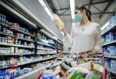 una mujer hace la compra en un supermercado con una mascarilla