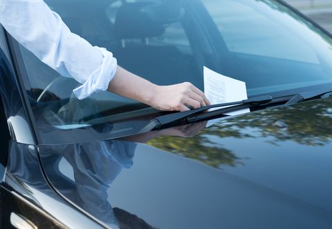 la imagen muestra una mano cogiendo una multa de un coche para ilustrar un reportaje sobre mgs seguros