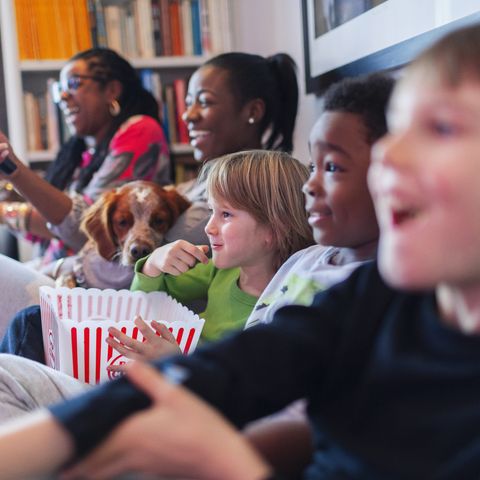 Multi-ethnic family watching movie and eating popcorn