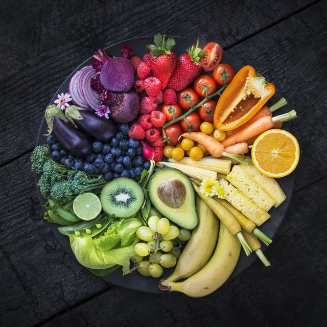 multicoloured fruit and vegetables in a black bowl on a burnt surface
