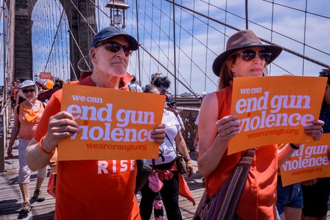 people wearing orange and holding signs that read we can end gun violence