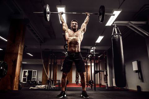 Muscular Fitness Man Doing Deadlift WIth A Barbell Over His Head In Modern Fitness Center