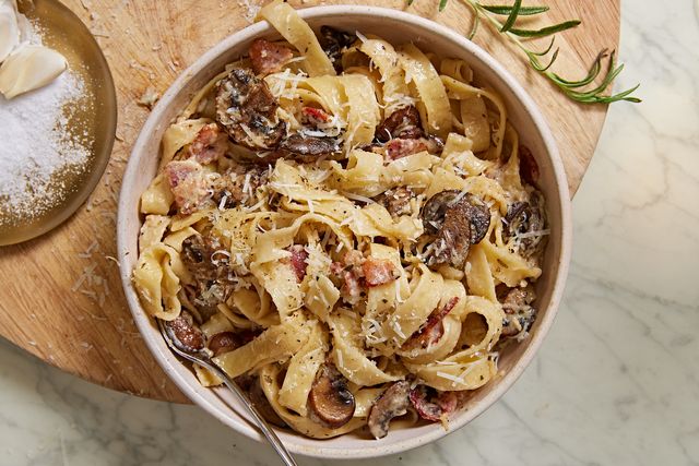 mushroom and bacon tagliatelle pasta topped with parmesan in a white bowl