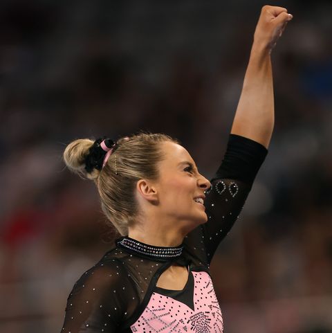 mykayla skinner fist pumping in a black and pink sparkly leotard