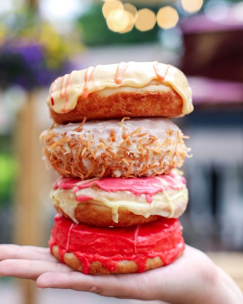 stack of 4 donuts with pink icing in an open palm
