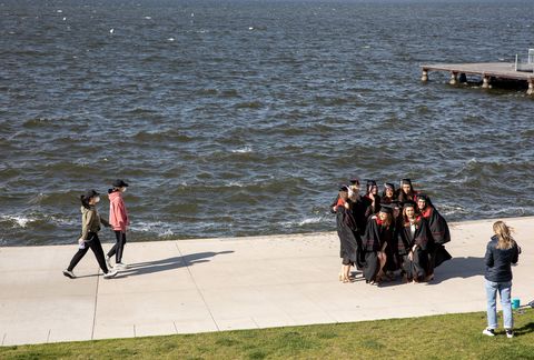 매디슨에있는 위스콘신 대학교에서 졸업 한 학생들은 2020 년 5 월 8 일에 가면과 함께 지나가는 두 명의 다른 행인들이 기념 조합 테라스에서 단체 사진을 위해 포즈를 취함