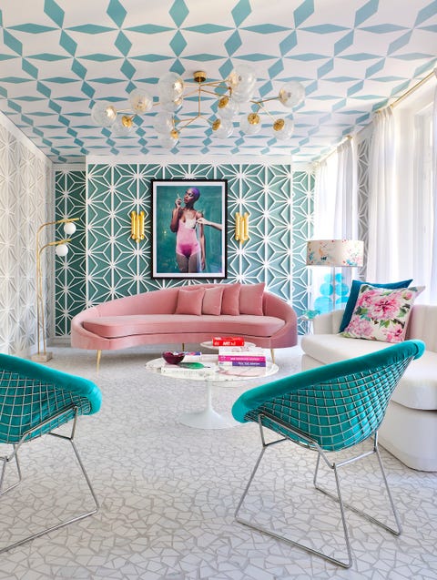 Living room with white mosaic floor, pink sofa, teal armchairs, teal and white latticed walls and brass light fittings