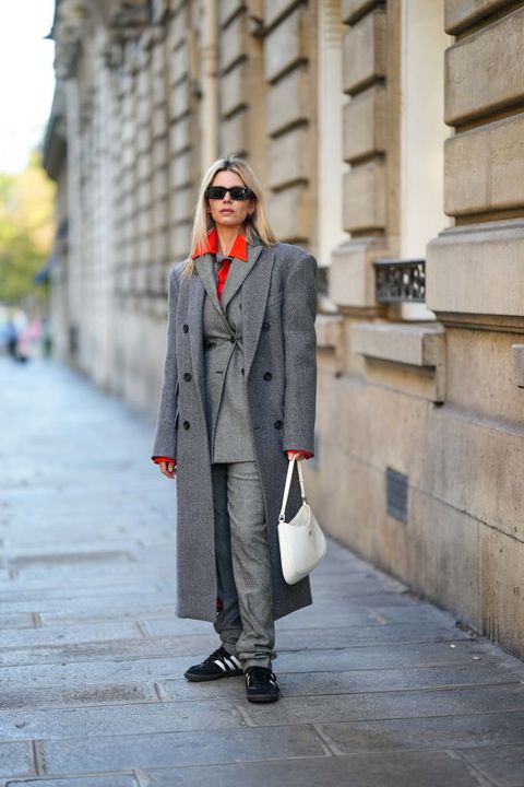 vrouw in grijs pak met grijze mantel poseert in parijs