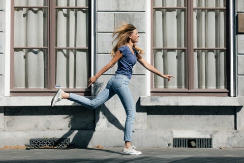 Holanda, Maastricht, joven rubia y feliz corriendo por un edificio de la ciudad