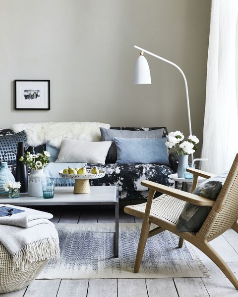 neutral living room, sitting room with cushions on the blue patterned sofa, a white floor lamp bent over the sofateamdrips, spotsandsplatter patterns foranimpressionistic look thatâ€™scontemporary andrelaxed