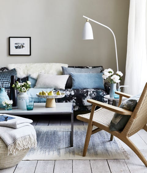 Neutral, relaxed living room sitting room with cushions on the blue patterned sofa, a white floor lamp bent over the sofateamdrips, spotsandsplatter patterns foranimpressionistic look that’scontemporary andrelaxed