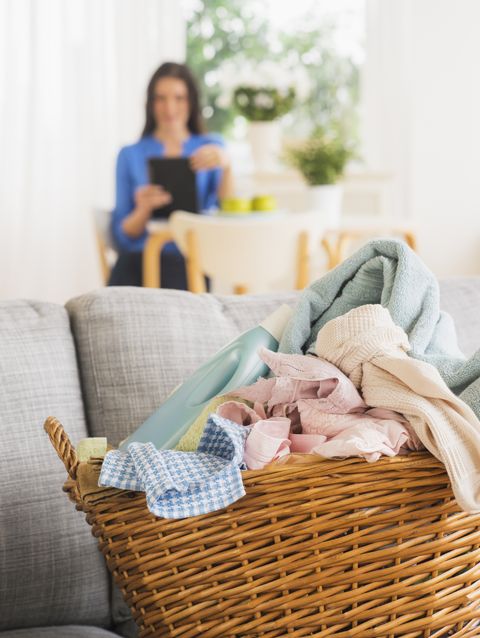 USA, New Jersey, Jersey City, Laundry basket on sofa and woman in background