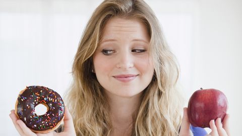 USA, New Jersey, Jersey City, Young woman choosing between donut and apple