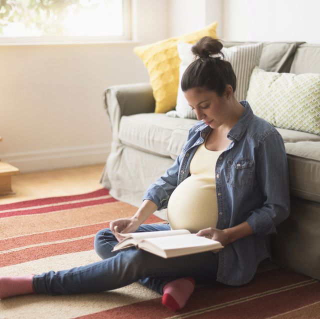 mujer embarazada sentada leyendo un libro