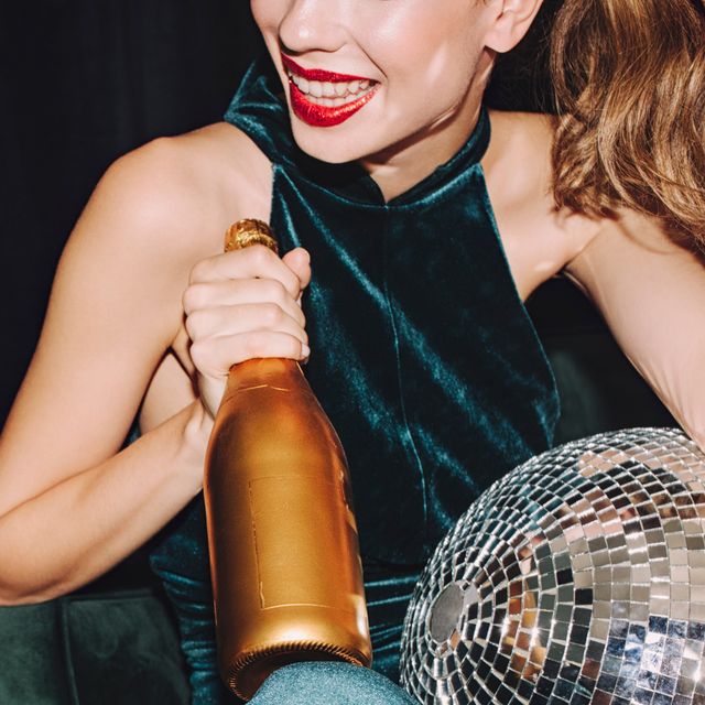 woman in dark green velvet dress with disco ball and champagne