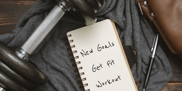 new year's goals and resolution written on notepad, with dumbbell and satchel man's bag on rustic wood