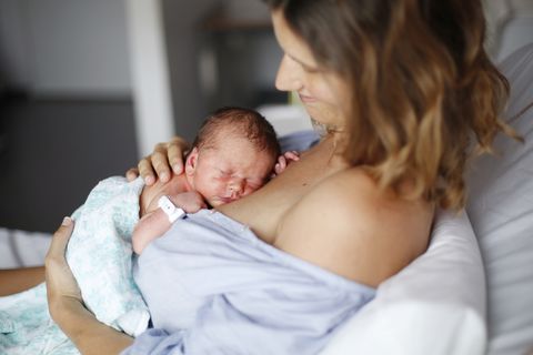 una mujer recién parida abraza a su recién nacido en la cama del hospital