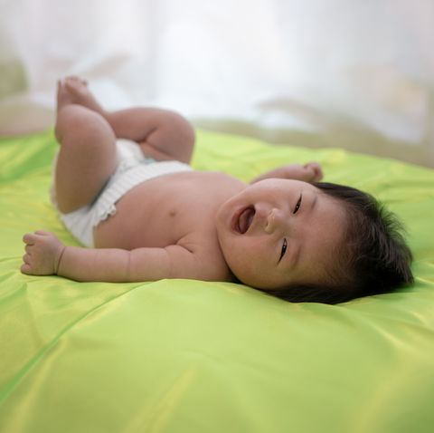 baby feeling happy on green bed
