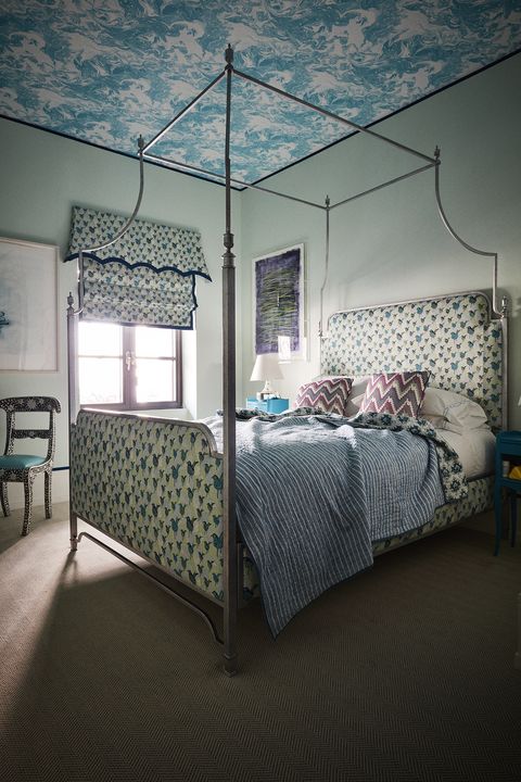 Blue bedroom with bird print tapestry and four-poster bed
