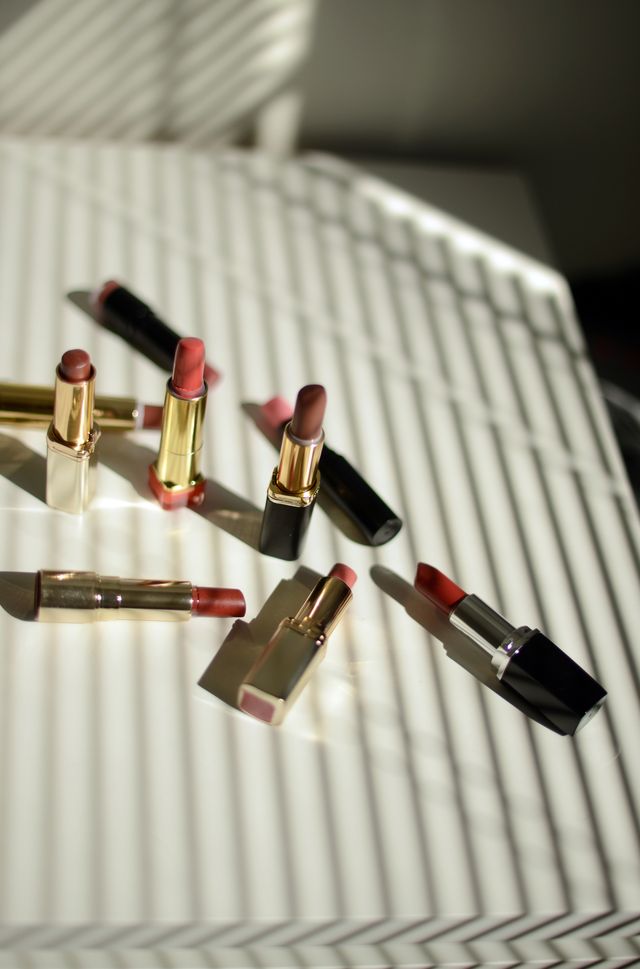 nine different lipsticks on a white shelf in a beautiful sunlight coming through blinds