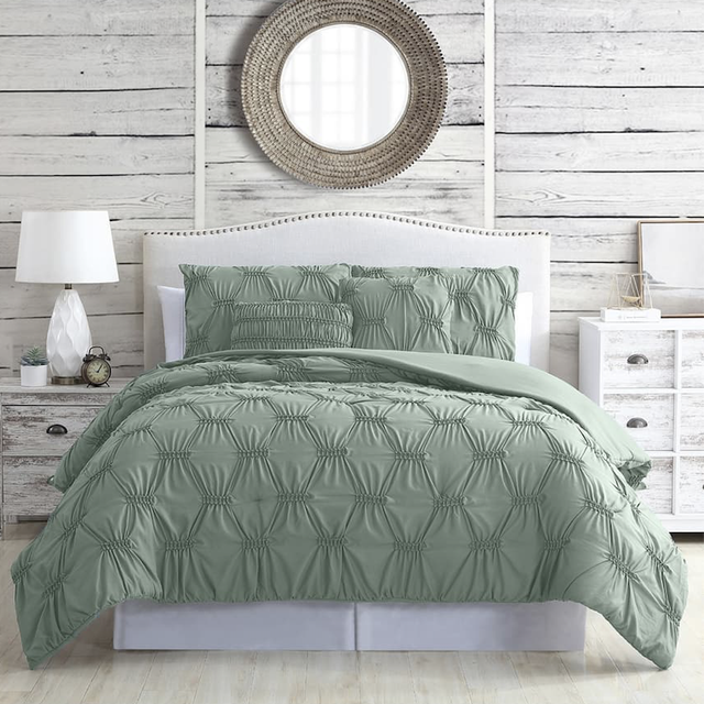 bedroom with green textured bedding, circular mirror, lamps