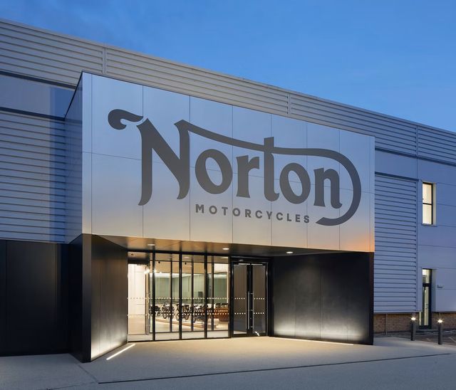 a metal clad industrial building with "norton motorcycles" written above the doorway entrance
